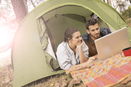 couple using a laptop in a camping tent